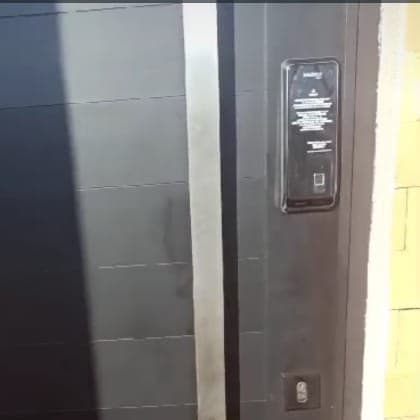 Fechadura digital instalada numa porta pivotante preta, ao lado do puxador
